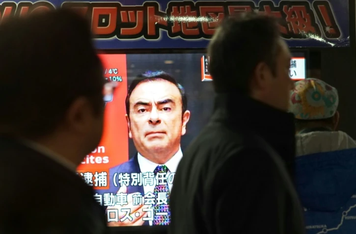 Des piétons passent devant un écran de télévision sur lequel apparaît le visage de Carlos Ghosn, ex-PDG de Nissan, le 21 décembre 2018 à Tokyo, au Japon