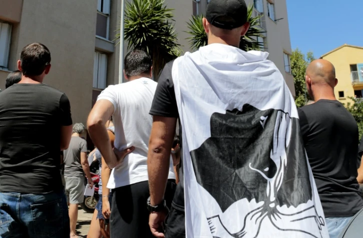Un homme arbore un drapeau corse pendant une manifestation à la cité des Monts à Lupino, le 14 août 2016, après une rixe sur une plage à Sisco