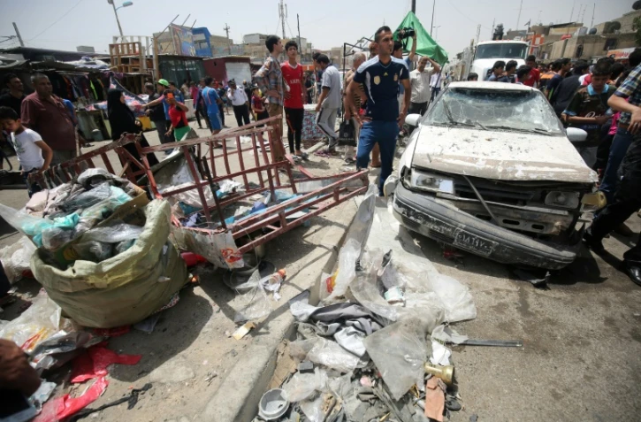 Des passants constatent les dégâts après l'explosion d'une voiture piégée près d'un marché du grand quartier chiite Sadr City, dans le nord de Bagdad le 11 mai 2016