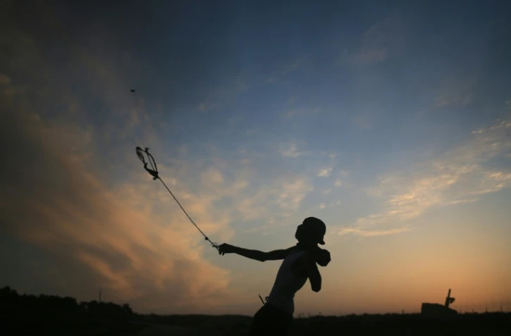 Un jeune palestinien de Gaza utilise une fronde pour lancer des pierres contre des soldats israéliens, le 13 octobre 2015 à la frontière entre Gaza et Israël