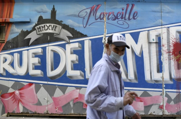 Un homme portant un masque devant un graffiti à Marseille, France, le 14 septembre 2020