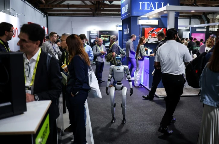 Un robot parmi des visiteurs au salon de l'IA Ă Londres, le 11 juin 2025