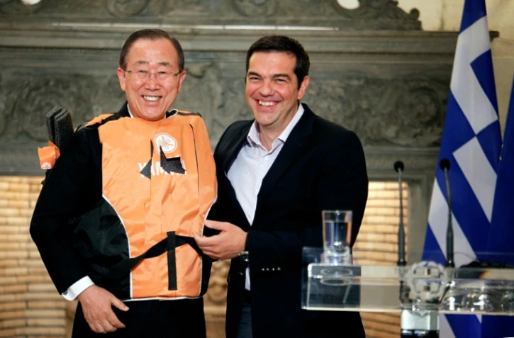 Le secrétaire général de l'ONU Ban Ki-moon (g) en gilet de sauvetage offert par le Premier ministre grec Alexis Tsipras (d) comme un  "symbole" des traversées périlleuses des migrants, le 18 juin à Athènes