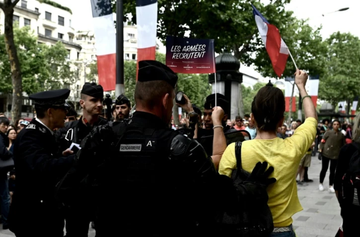 Des gendarmes entourent une jeune femme habillée en jaune criants des slogans anti-Macron, lors du défilé du 14 juillet 2019 sur les Champs-Elysées à Paris