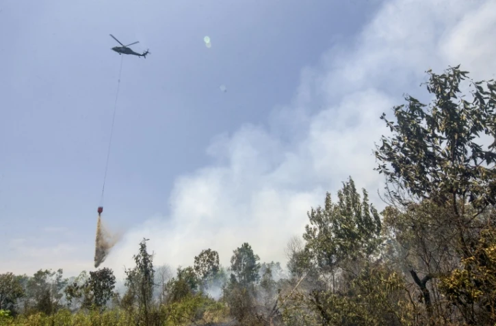Un hélicoptère largue de l’eau sur des forêts et des terres en feu dans les zones de Tegal Arum et Guntung Damar, à Banjarbaru, dans la province de Kalimantan du Sud, en Indonésie, le 19 septembre 2026