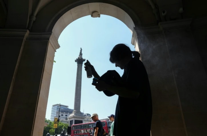 Une femme se protège de la chaleur du soleil, dans l'ombre d'une entrée sur Trafalgar Square, à Londres, le 8 juillet 2026