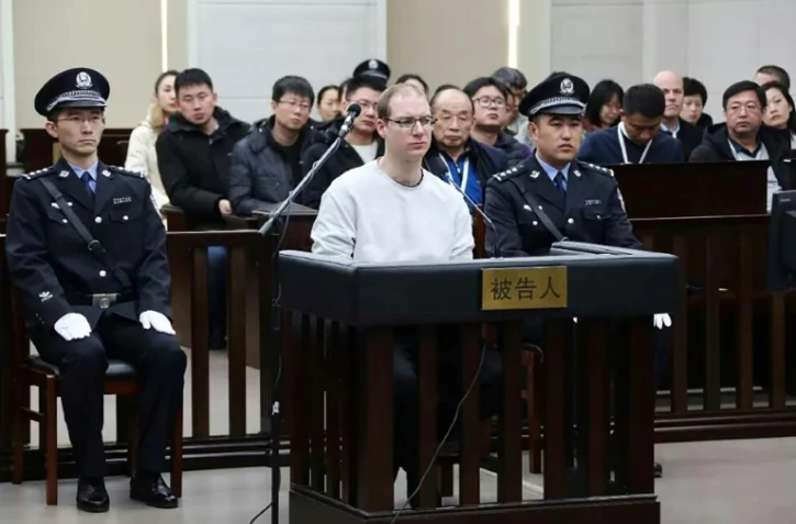 Photo fournie par le tribunal populaire de Dalian, en Chine, le 14 janvier 2019 du Canadien Robert Lloyd Schellenberg (C) pendant son procès pour trafic de drogue