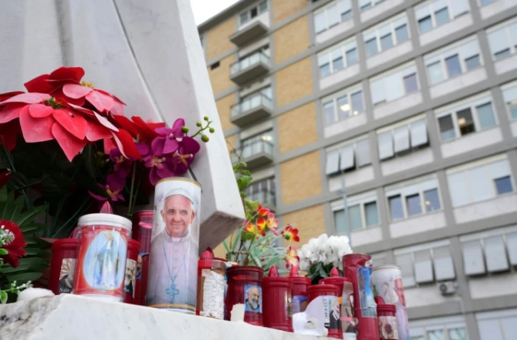 Des bougies déposées au pied d'une statue du pape Jean-Paul II à l'extérieur de l'hôpital Gemelli où le pape François est hospitalisé à Rome, le 20 février 2025
