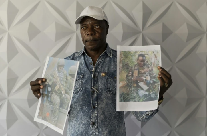 Un proche montre des photos de Kényans enrôlés de force dans l'armée russe en Ukraine lors d'une conférence de presse à Nairobi, le 27 janvier 2026, pour exiger du gouvernement leur rapatriement