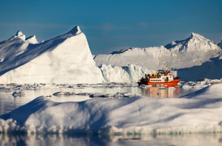 Un bateau de touristes navigue au milieu des icebergs dans la baie de Disko, le 1er juillet 2022 à Ilulissat, au Groenland 