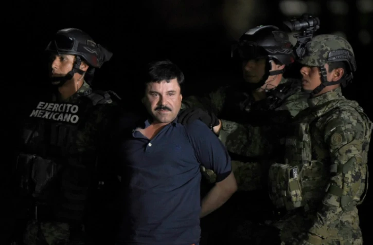 Le baron de la drogue El Chapo maintenu par des policiers peu après son arrestation, le 8 janvier 2016 sur le tarmac de l'aéroport de Mexico