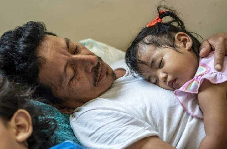 Jose Eliberto Hernandez Lopez, allongé avec sa fille Enya, dans un refuge pour migrants, à Matamoros, au Mexique, le 26 mai 2021