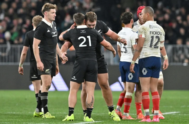 Le Français Gaël Fickou (d.) regarde les joueurs néo-zélandais célébrer leur victoire lors du premier test-match international de rugby entre la Nouvelle-Zélande et la France au stade Forsyth Barr de Dunedin, le 5 juillet 2025