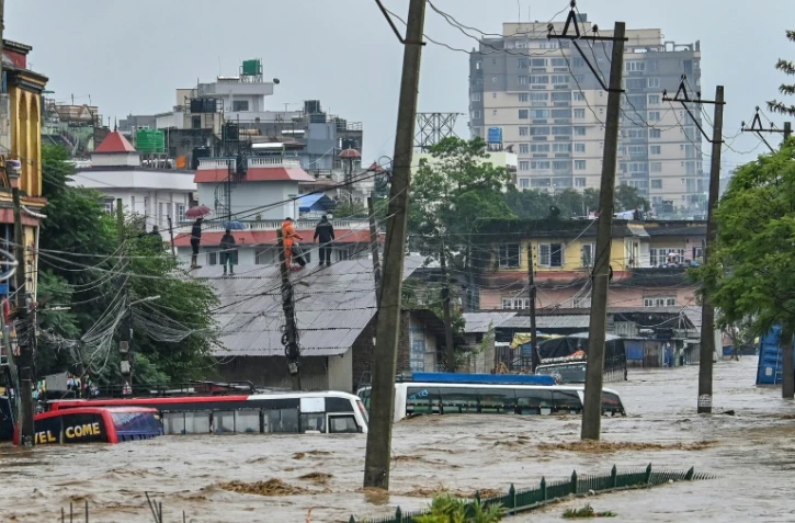 Des habitants réfugiés sur un toit alors que leur quartier est submergé par les eaux après le débordement de la rivière Bagmati à Katmandou, le 28 septembre 2024