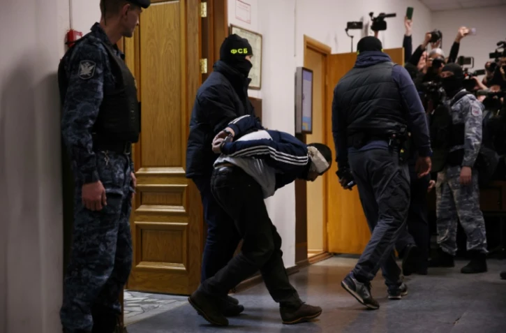 Un homme soupçonné d'avoir participé à l'attaque de la salle de concert Crocus City Hall, est escorté par des forces de l'ordre russes avant son audience de détention provisoire au tribunal du district de Basmanny, le 24 mars 2024 à Moscou