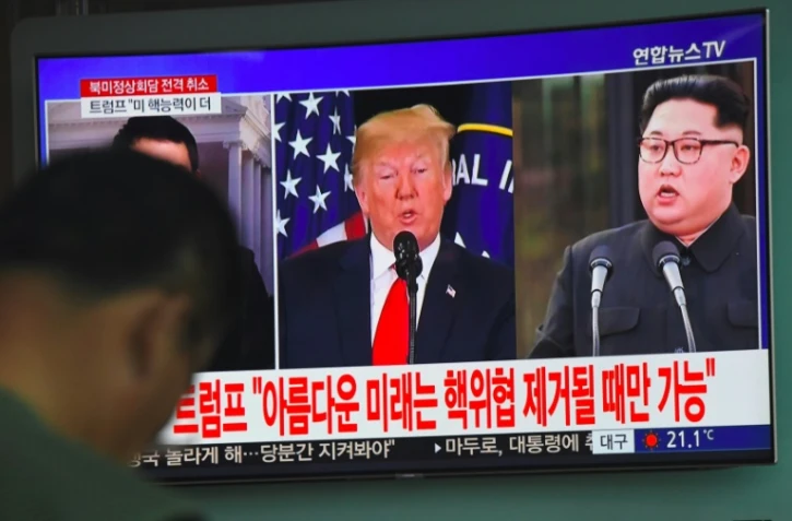 Les photos du président américain Donald Trump (g) et du leader nord-coréen Kim Jong Un sur un écran de télévision dans une gare de Séoul, le 25 mai 2018, après l'annulation du sommet entre les deux dirigeants