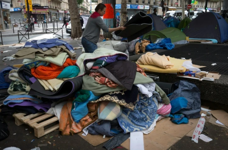Des bénévoles récupèrent les tentes en bon état lors de l'évacuation d'un campement de migrants le 16 juin 2016 à Paris