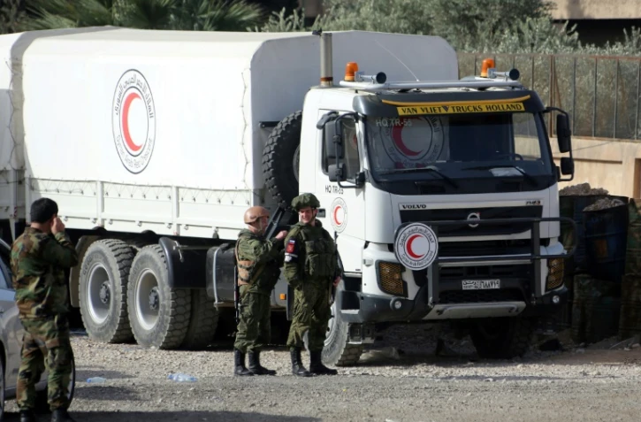 Des soldats russes se tiennent le 8 mars 2018 à un check-point à la péripéhérie de Damas près d'un camion d'aide humanitaire destinée aux habitants d'une enclave rebelle