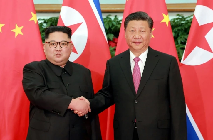 Photo fournie le 9 mai 2018 par l'agence nord-coréenne Kcna du leader nord-coréen Kim Jong Un et du président chinois Xi Jinping (d), lors d'une rencontre à Dalian, en Chine