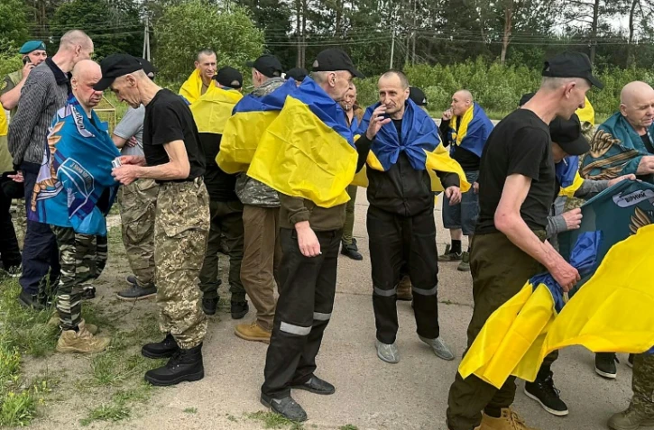 Photo non datée publiée sur la chaîne Telegram officielle du président ukrainien Volodymyr Zelensky, le 19 juin 2025, de prisonniers de guerre ukrainiens (PG) enveloppés dans le drapeau national après un échange de prisonniers dans un lieu non divulgué en Ukraine