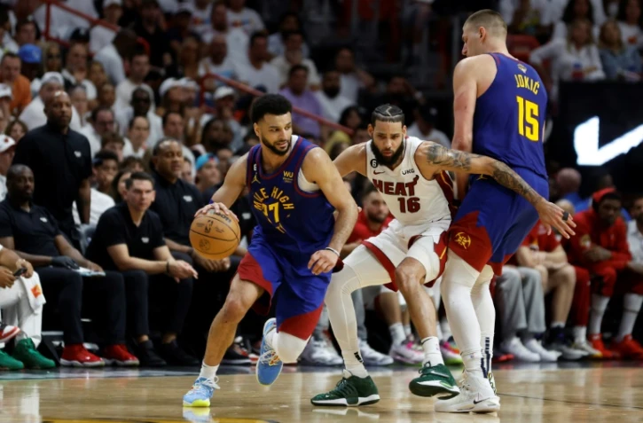 Jamal Murray (g.) des Denver Nuggets profite d'un écran posé par son équipier Nikola Jokic (d.) devant Caleb Martin (c.) du Miami Heat pendant le troisième match des Finales NBA 2023, à Miami, le 7 juin 2023