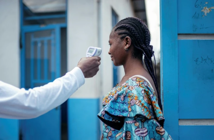 Un membre du personnel de l'hôpital CBCA Virunga prend la température d'une visiteuse à l'aide d'un thermomètre infrarouge sans contact avant de l'autoriser à entrer dans l'hôpital de Goma, en République démocratique du Congo, le 17 mai 2026. 
