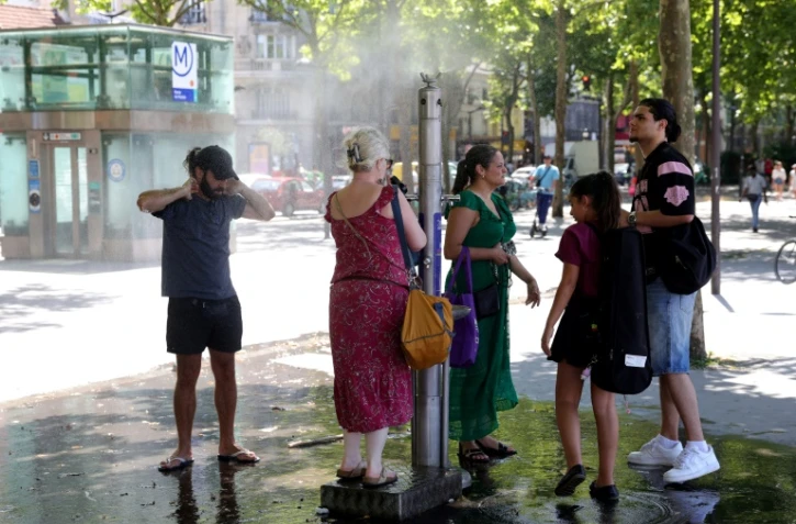 Des passants se rafraîchissent grâce à une fontaine brumisante à Paris, le 21 juin 2025