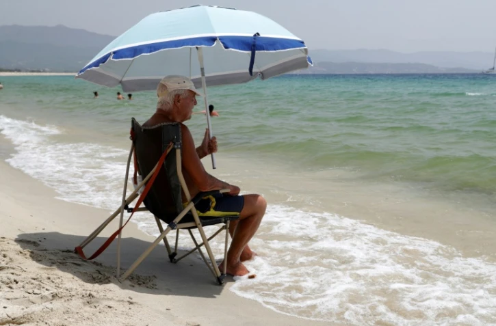 Un homme sous un parasol Ă plage Ă Ajaccio le 19 juillet 2023