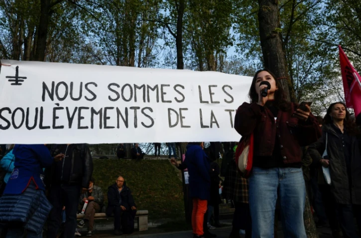 Une manifestante prend la parole devant une banderole du collectif écologiste "Les Soulèvements de la terre" à Paris, le 19 avril 2023