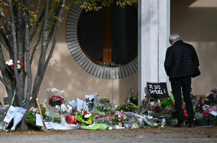Un homme se recueille devant le collège du Bois d'Aulne à Conflans-Sainte-Honorine, où enseignait Samuel Paty, le 19 octobre 2020 