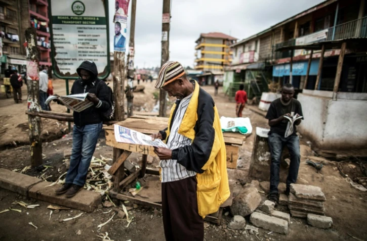 Des kenyans lisent le journal, dans l'attente des résultats définitifs de l'élection présidentielle, dans le bidonville de Kawangare à Nairobi, le 10 août 2017