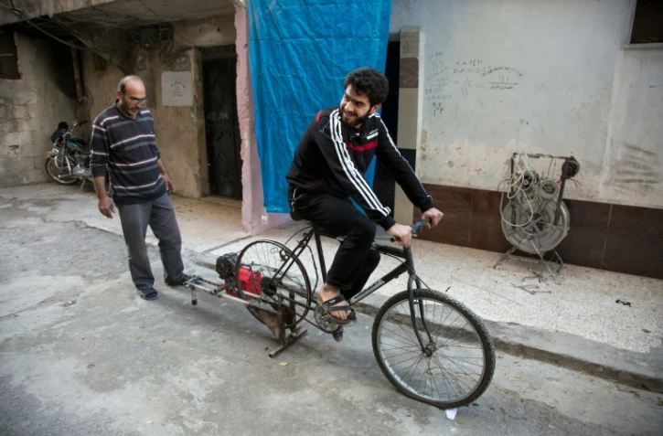 Un Syrien pédale sur un vélo relié à une vieille batterie pour produire de l'électricité, le 31 octobre 2016 à Alep