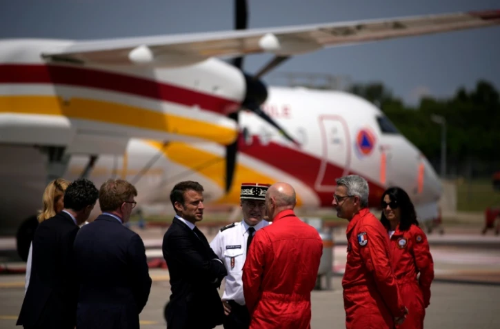 Le président Emmanuel Macron (c) écoute les agents de la sécurité civile lors de sa visite à la base aérienne des pompiers de Nîmes-Garons, le 2 juin 2023 à Garons, dans le Gard