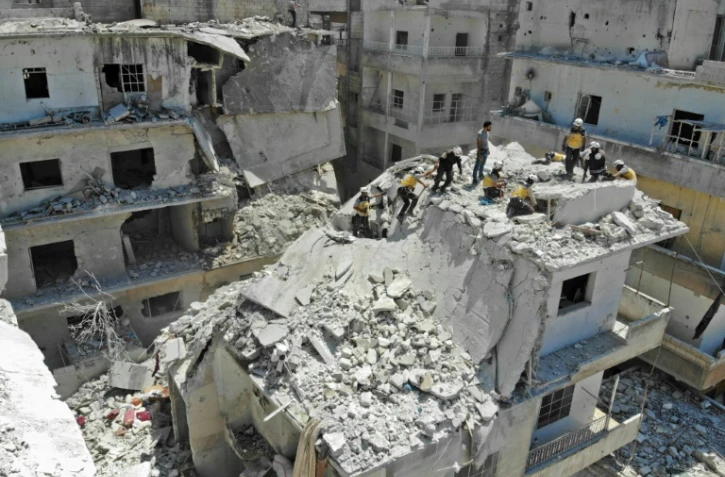 Des secouristes des Casques blancs cherchent des victimes à l'intérieur d'un immeuble visé par un raid du régime à Ariha, dans le nord-ouest en Syrie, le 27 juillet 2019