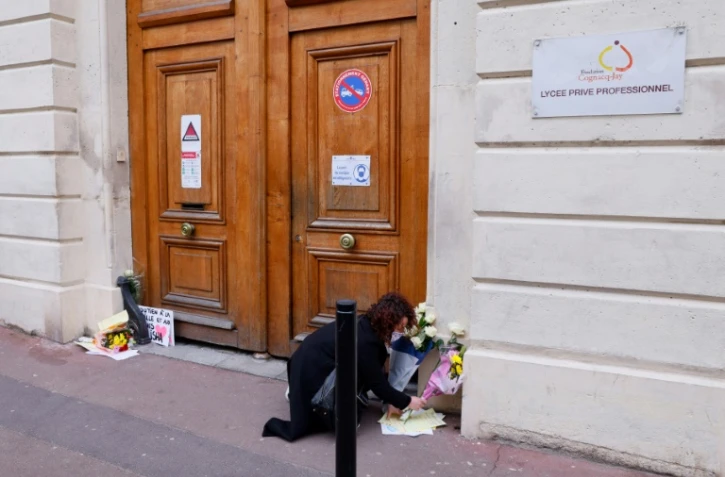 Une femme dépose des fleurs devant le lycée de la jeune Alisha à sa mémoire, le 10 mars 2021