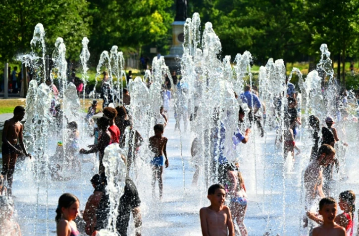 Des enfants se rafraîchissent dans les jets d'eau d'une fontaine à Reims, dans le nord-est de la France, le 1er juillet 2025