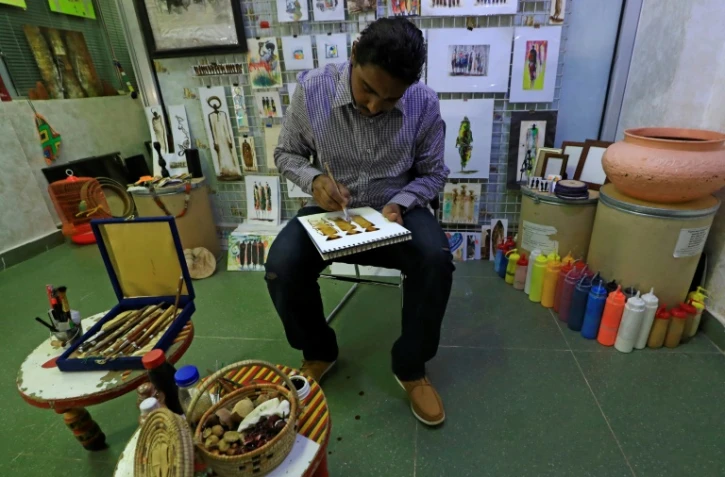 L'artiste soudanais Mouataz al-Fateh peint avec des couleurs issues de produits naturels dans sa galerie à Khartoum, le 15 avril 2022