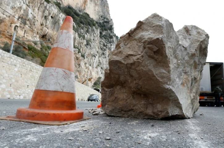Une voiture passe derrière un rocher tombé suite à un éboulement à Beaulieu-Sur-Mer le 10 février 2013