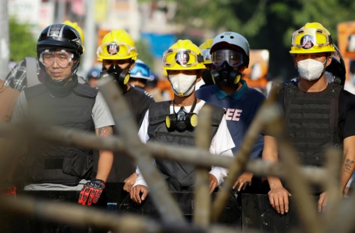 Des manifestants derrière une barricade font face aux forces de police, le 4 mars 2021 à Naypyidaw