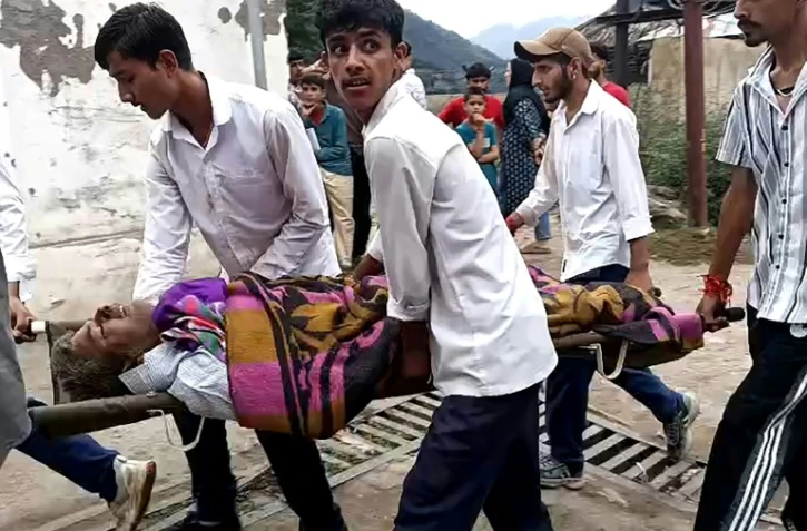 Des hommes transportent un blessé dans une civière à l'hôpital de Kishtwar en Inde le 14 août 2025 après des inondations au Cachemire 