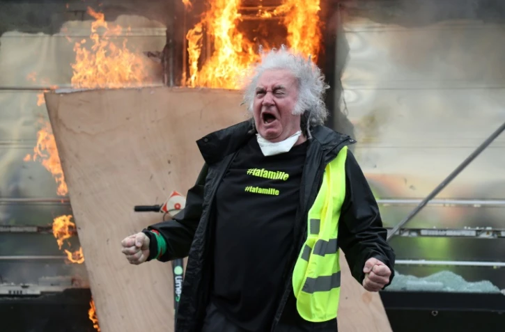 Un "gilet jaune" devant un kiosque à journaux en feu sur les Champs Elysées, à Paris, le 16 mars 2019