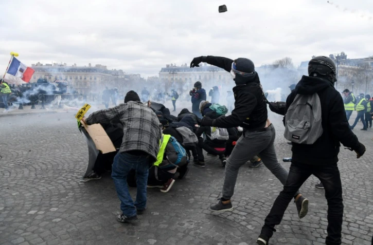 Des manifestants jettent des pavés sur les forces de l'ordre Place de l'Etoile à Paris, le 16 mars 2019