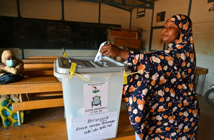 Une femme dépose son bulletin dans l'urne dans une salle classe transformée en bureau de vote à Niamey, le 21 février 2021 pour le second tour de la présidentielle
