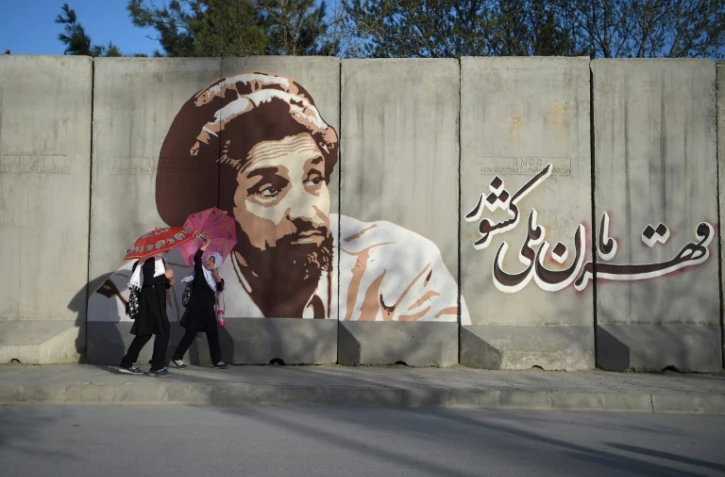 Des écolières passent devant un mur recouvert d'un portrait du commandant Massoud, le 7 avril 2019 à Kaboul