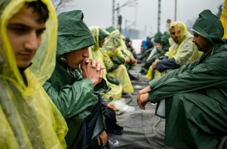 Un groupe de migrants sur des rails pendant une manifestation pour la réouverture de la frontière gréco-macédonienne, le 23 mars 2016