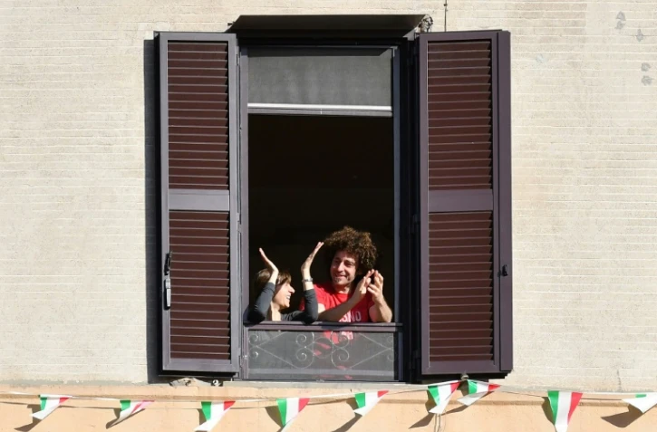 Des Italiens applaudissent depuis leur fenêtre l'assouplissement du confinement, à Rome le 3 mai 2020