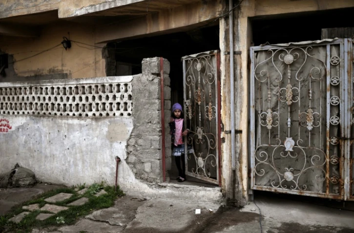 Une enfant regarde par une porte entrebâillée, le 2 mars 2017 à Mossoul pendant l'offensive entre les forces irakiennes et les jihadistes de l'EI