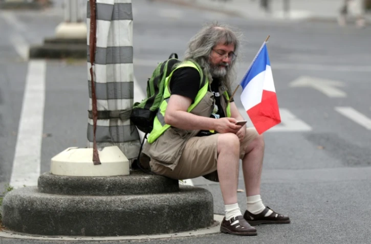Un homme tient un drapeau français lors d'une manifestation anti-pass sanitaire le 21 août 2021 à Paris
