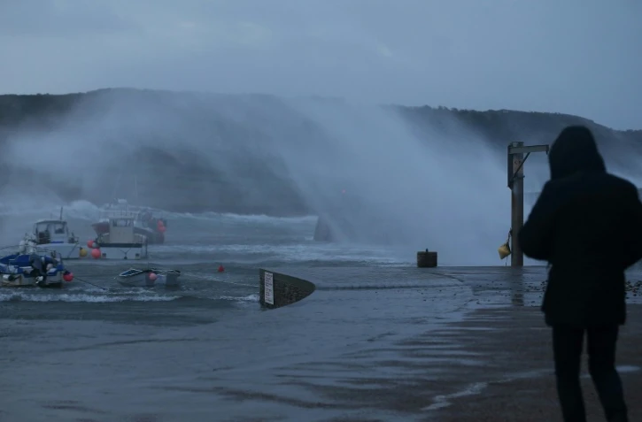 Une personne regarde les bateaux secoués par la houle lors d'une tempête à Auderville, le 8 février 2016 dans la Manche