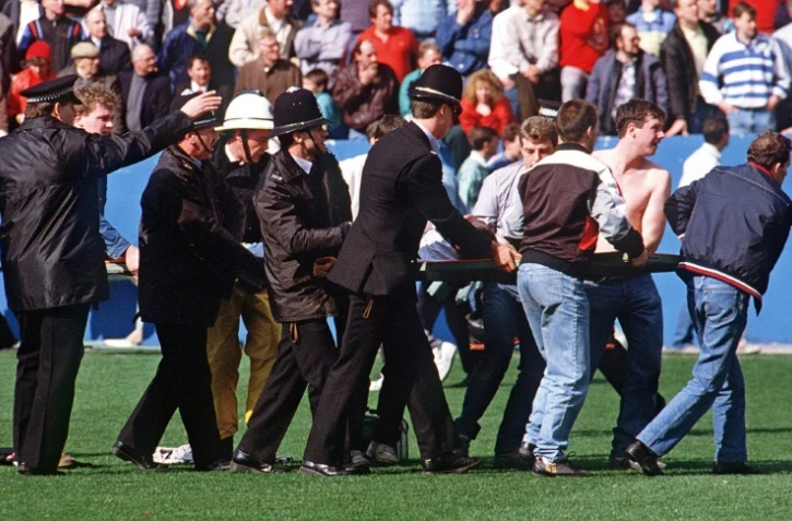 Des policiers transportent un supporteur blessé dans le stade de Hillsborough, le 15 avril 1989 à Sheffield, au Royaume-Uni